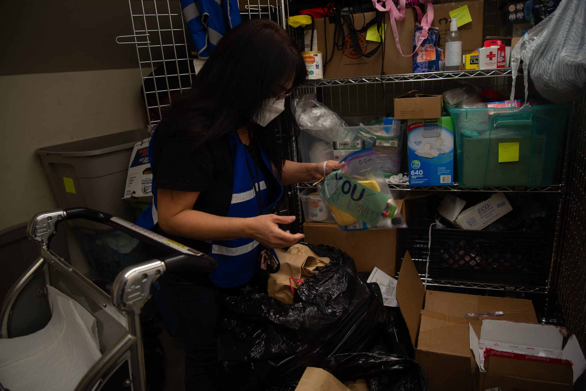 A woman wearing a face mask organizes item in a storage closet