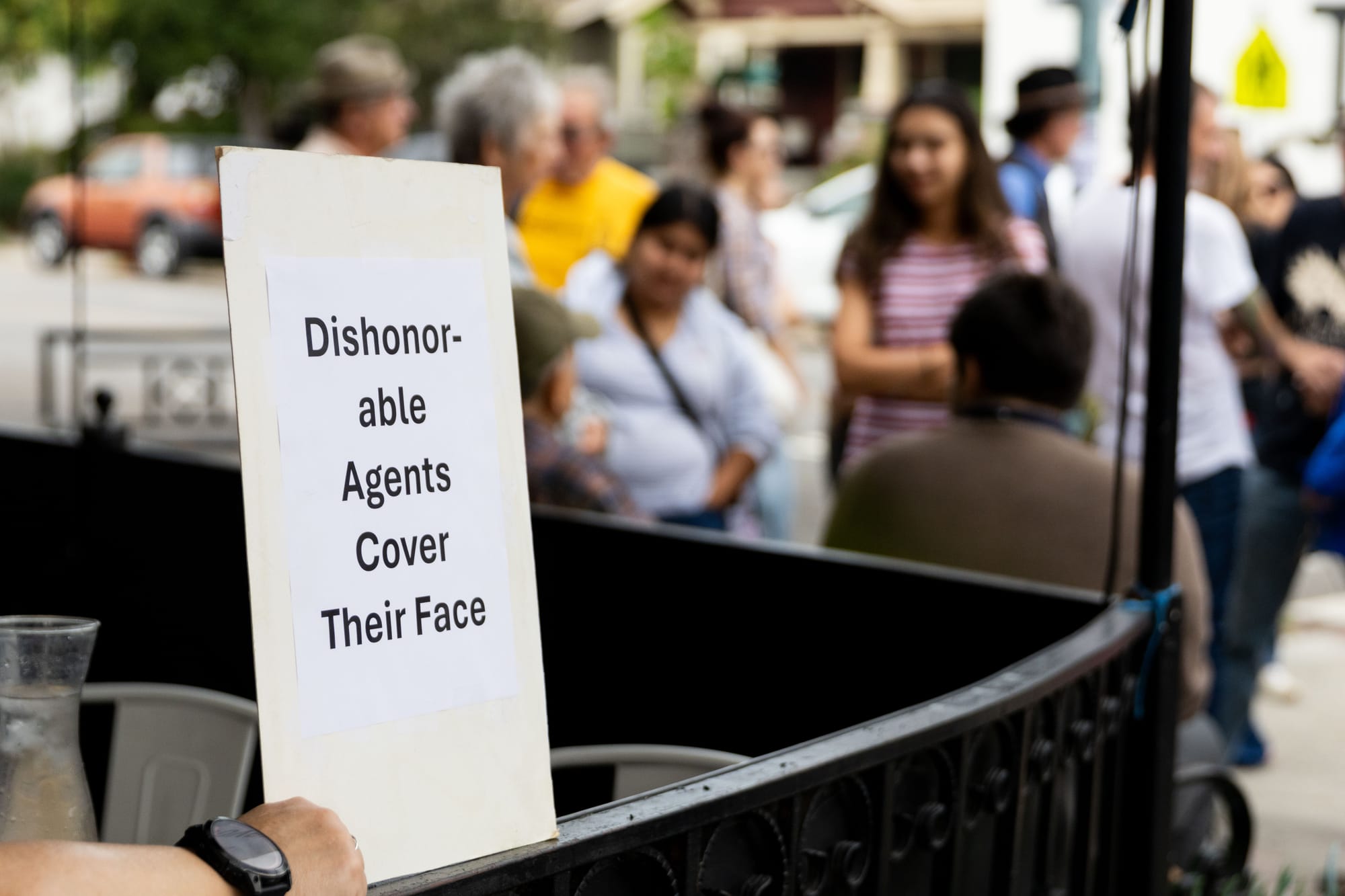A sign reads "Dishonorable Agents Cover Their Face"