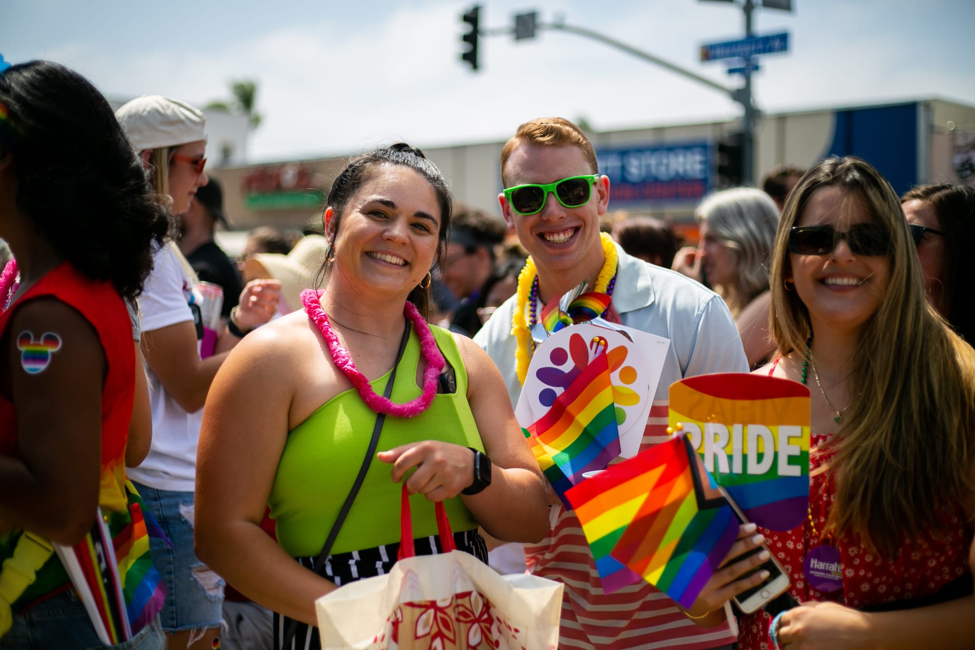 three people stand in a crowd holding rainbow flags