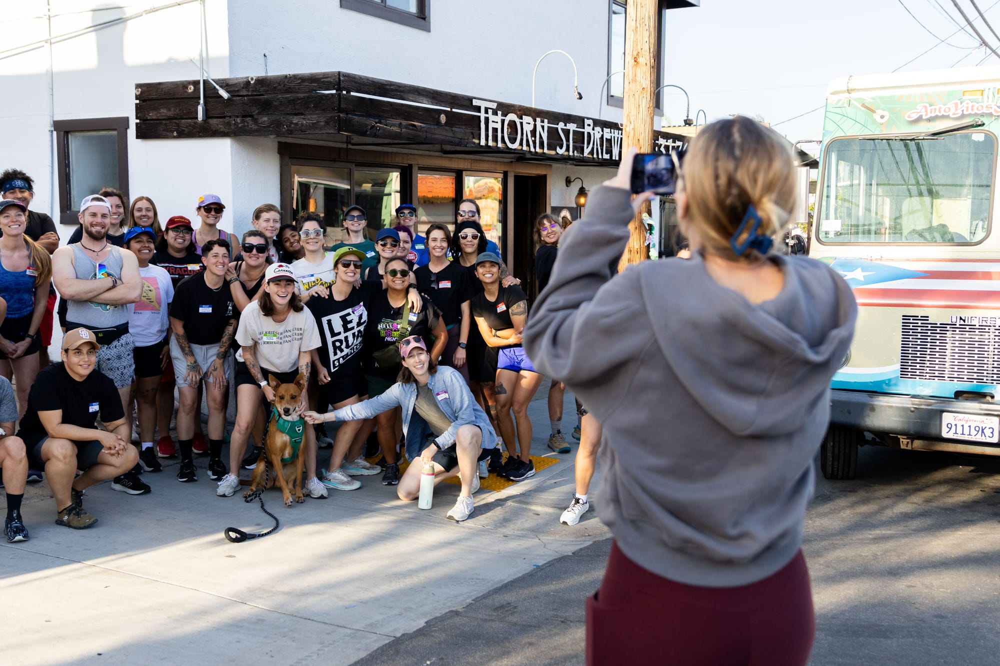 People pose for a group photo outside in front of Thorn St. Brewery and a food truck