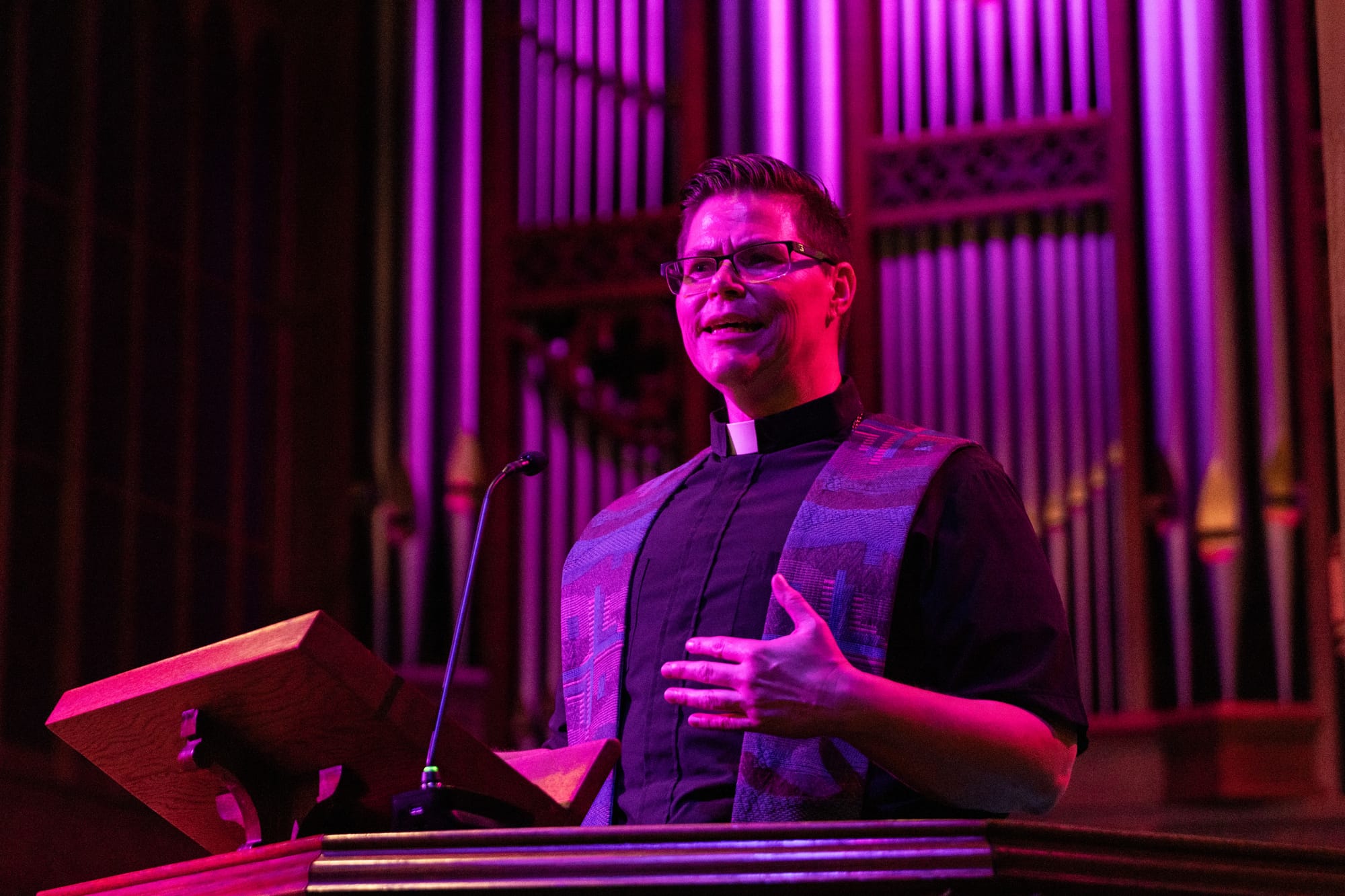 A pastor speaks on a pulpit in front of an organ in a church