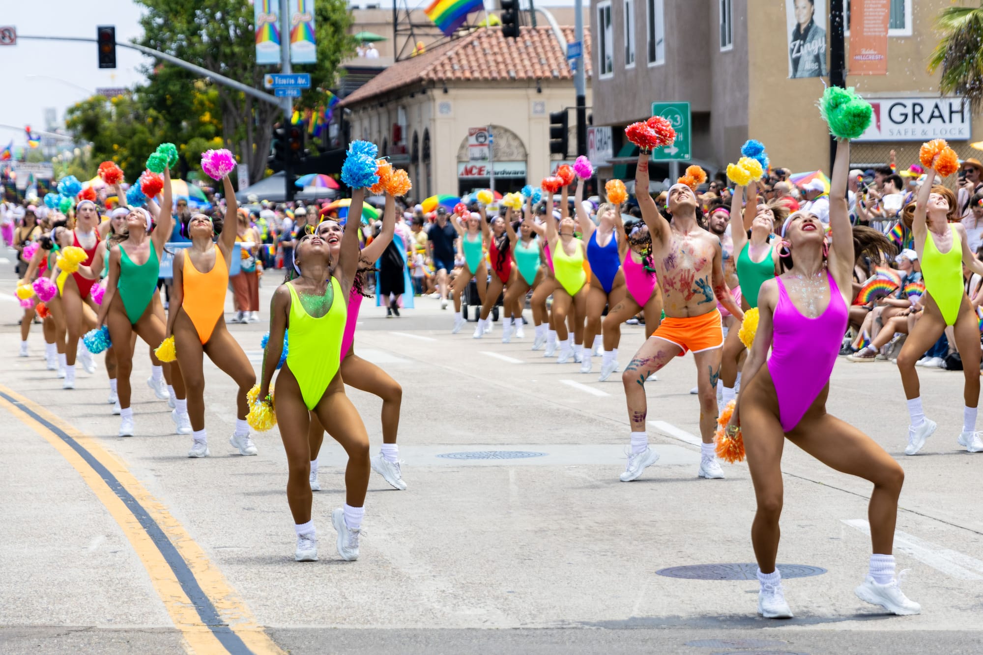 A group of people in neon leotards dance with pom poms 