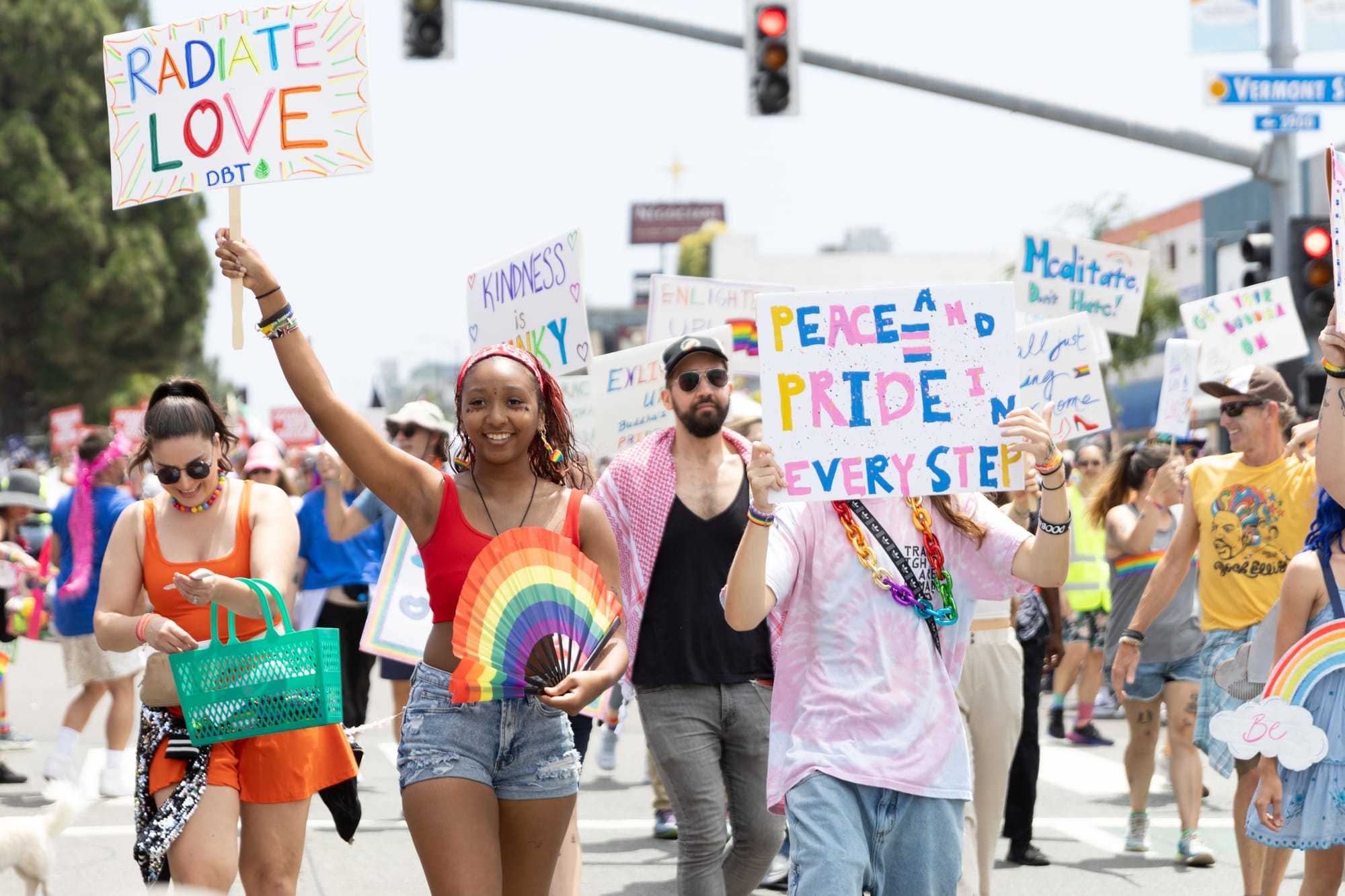 People hold signs painted with rainbow colors and trans pride flags that read "Peace and Pride in Every Step," "Radiate Love" and other messages