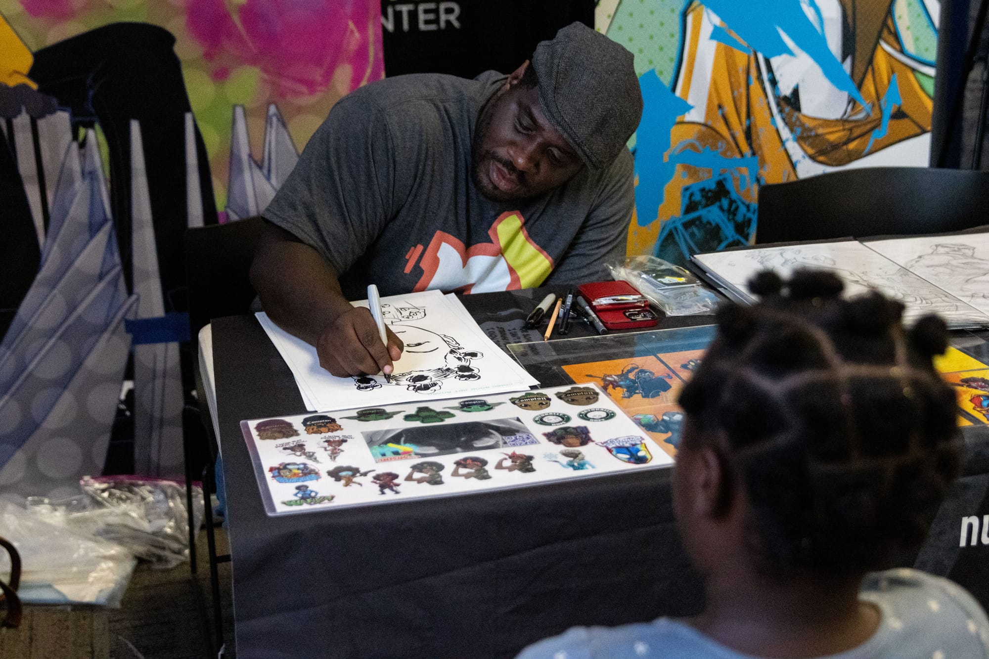 A man draws a caricature of a child at a table