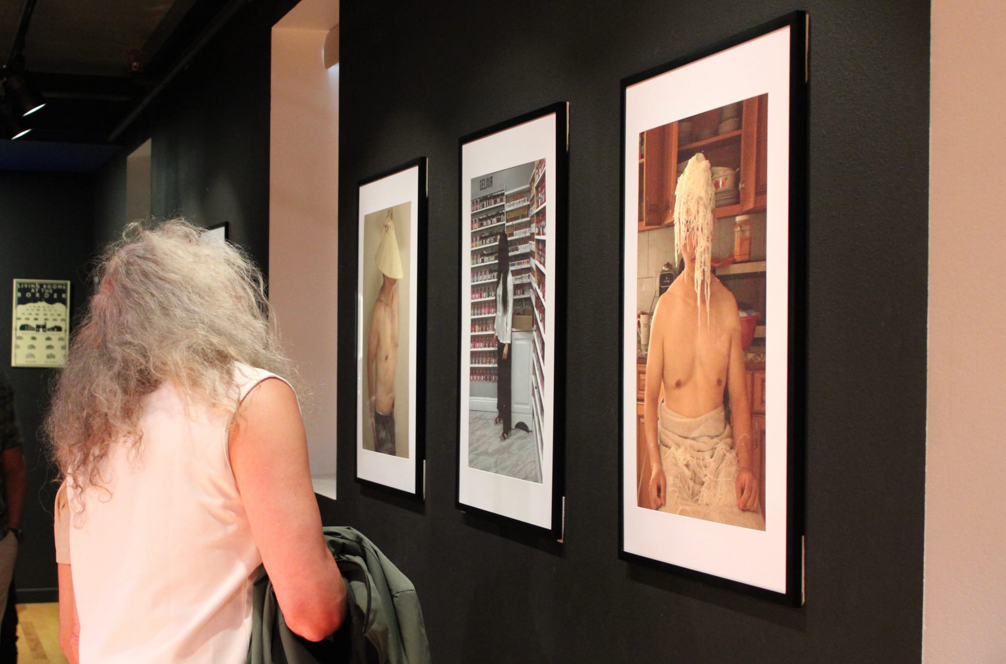 Someone looks at photographs on a gallery wall
