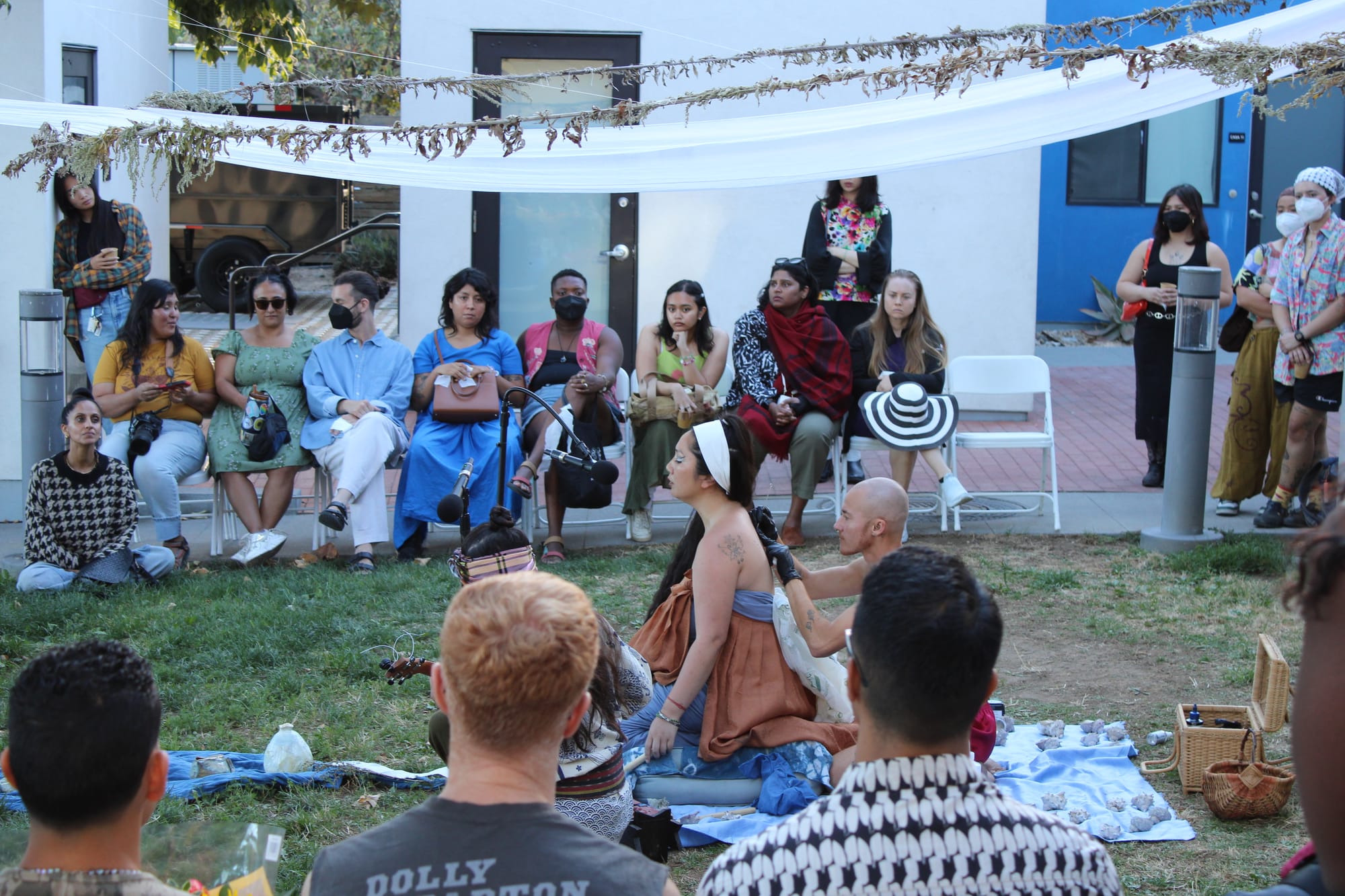 Someone sings while receiving a tattoo in front of an audience at an outdoor event