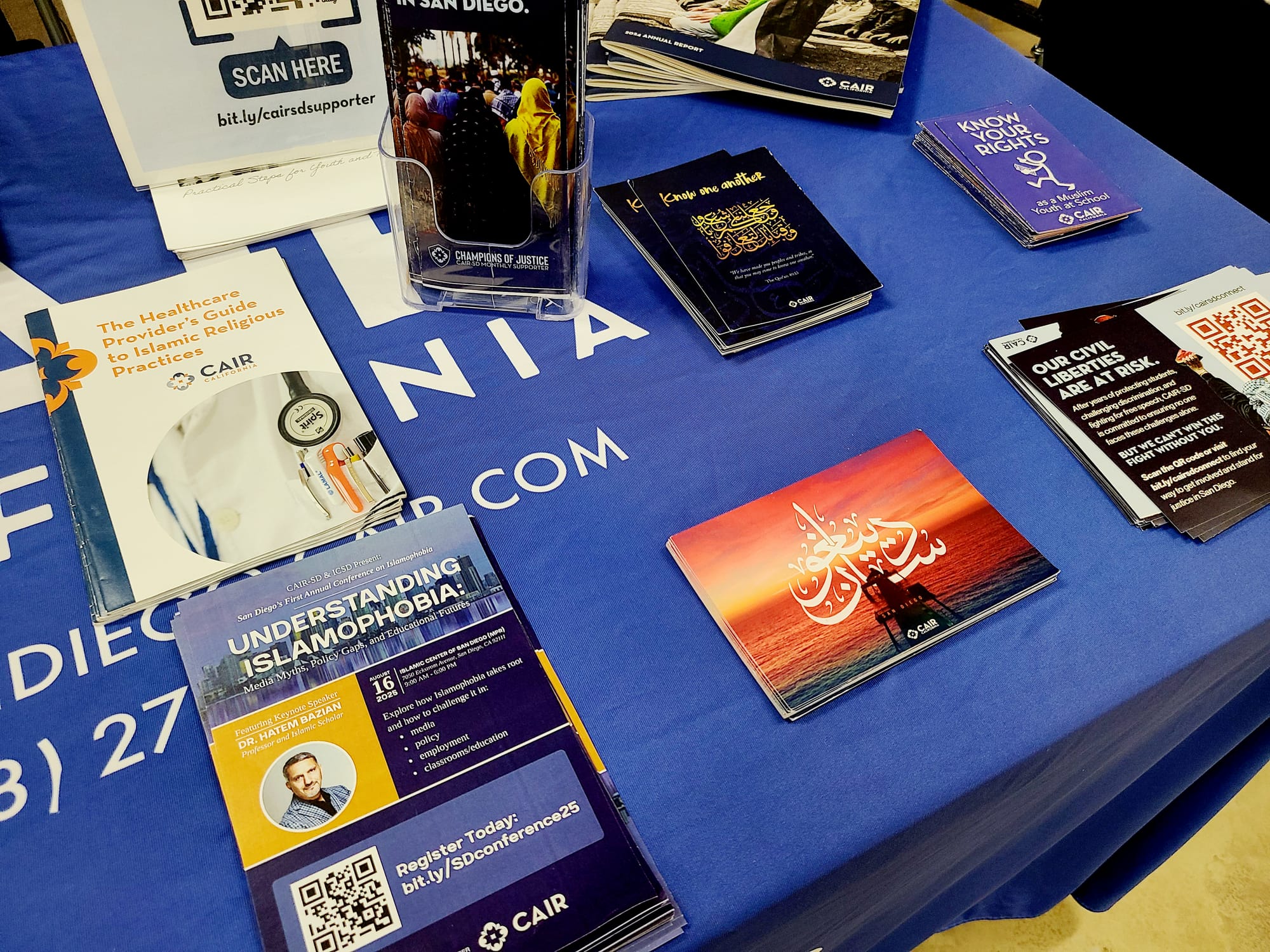 A blue tablecloth-covered table with flyers displayed on it