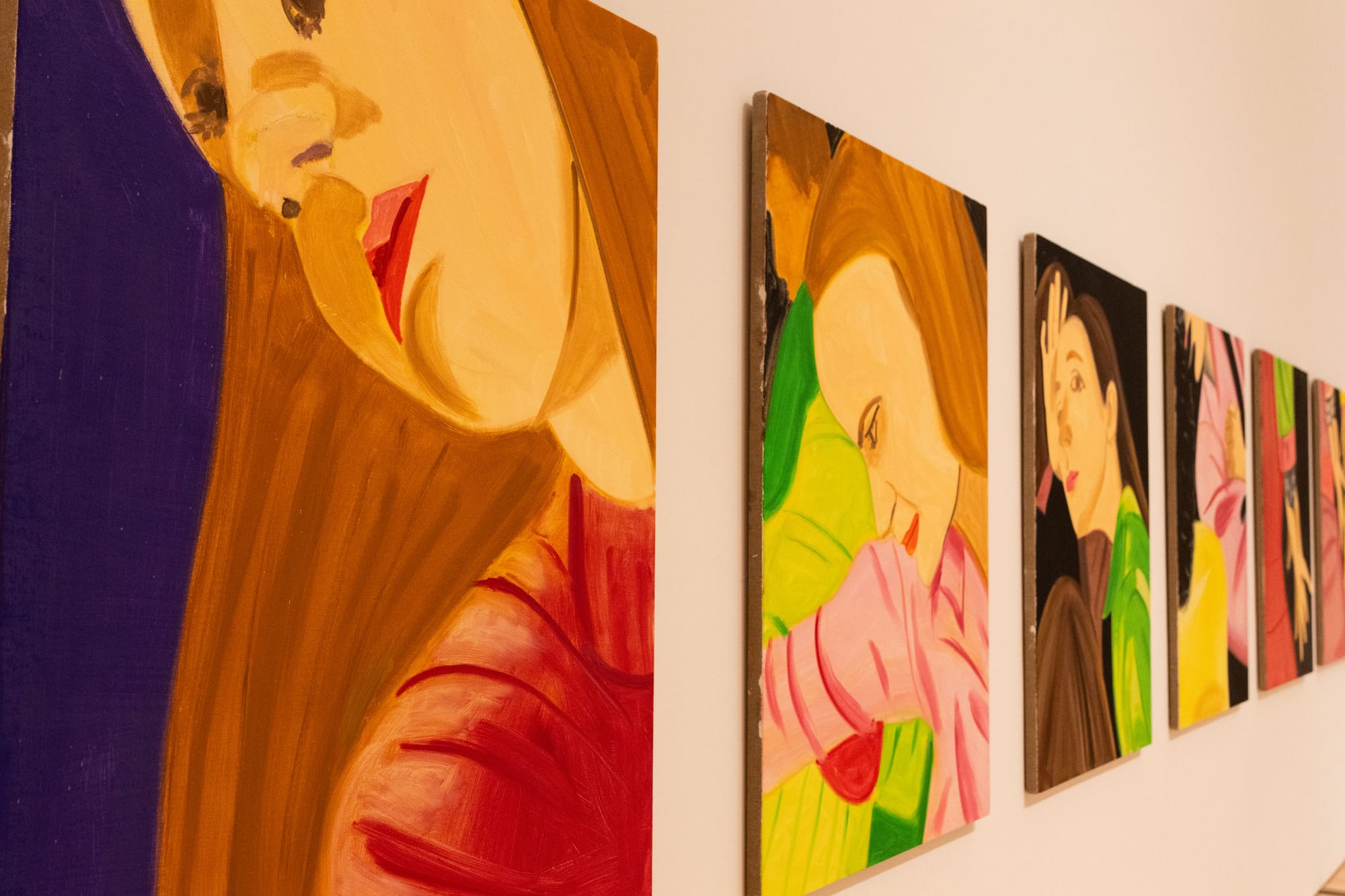 A series of colorful, closeup paintings of dancers are displayed on a museum wall