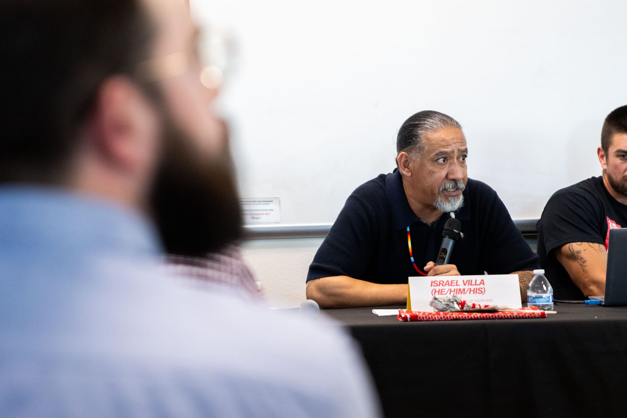 A man sits on a panel at an event speaking