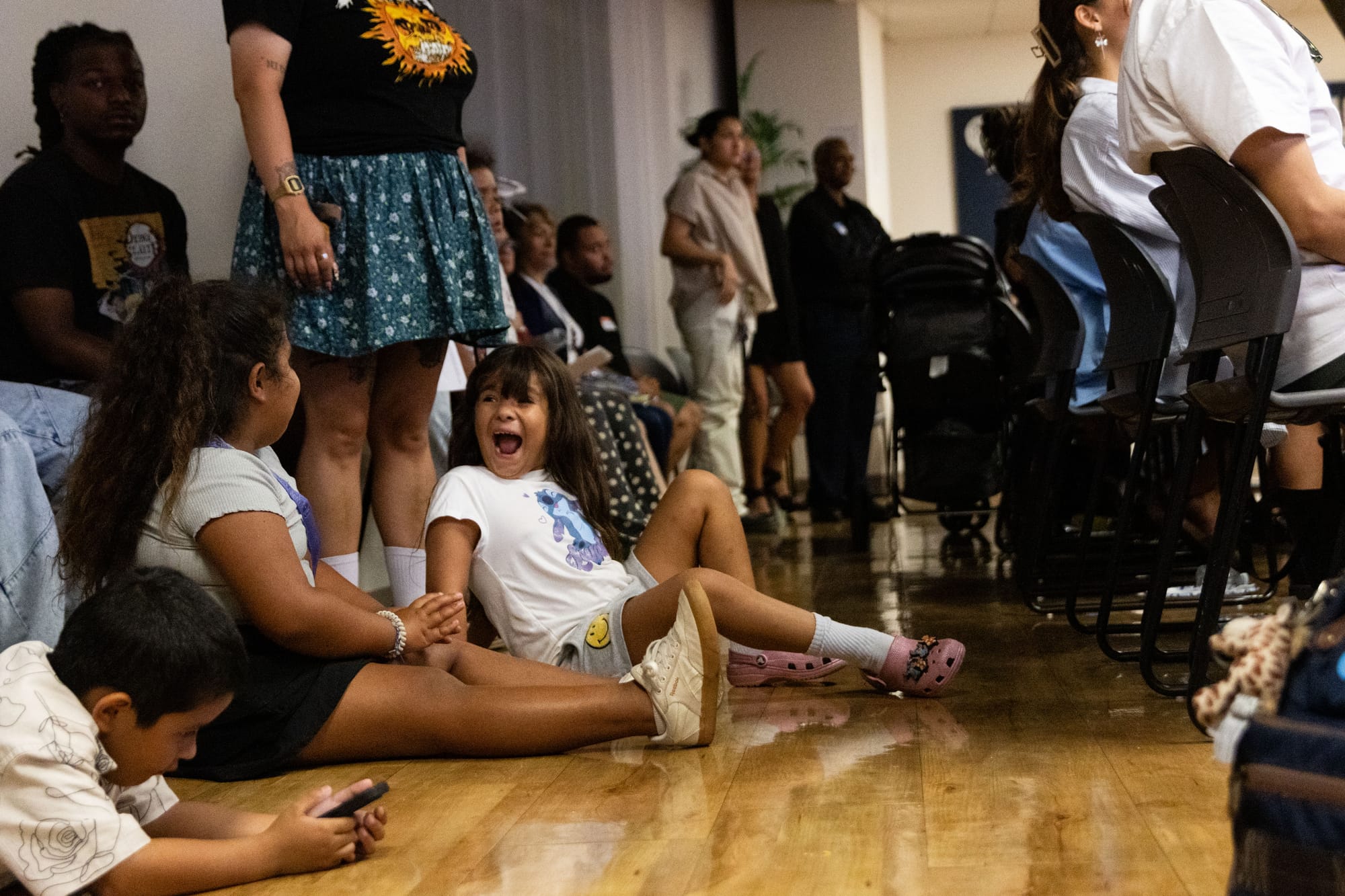Kids play on the floor while a crowd watches a panel discussion
