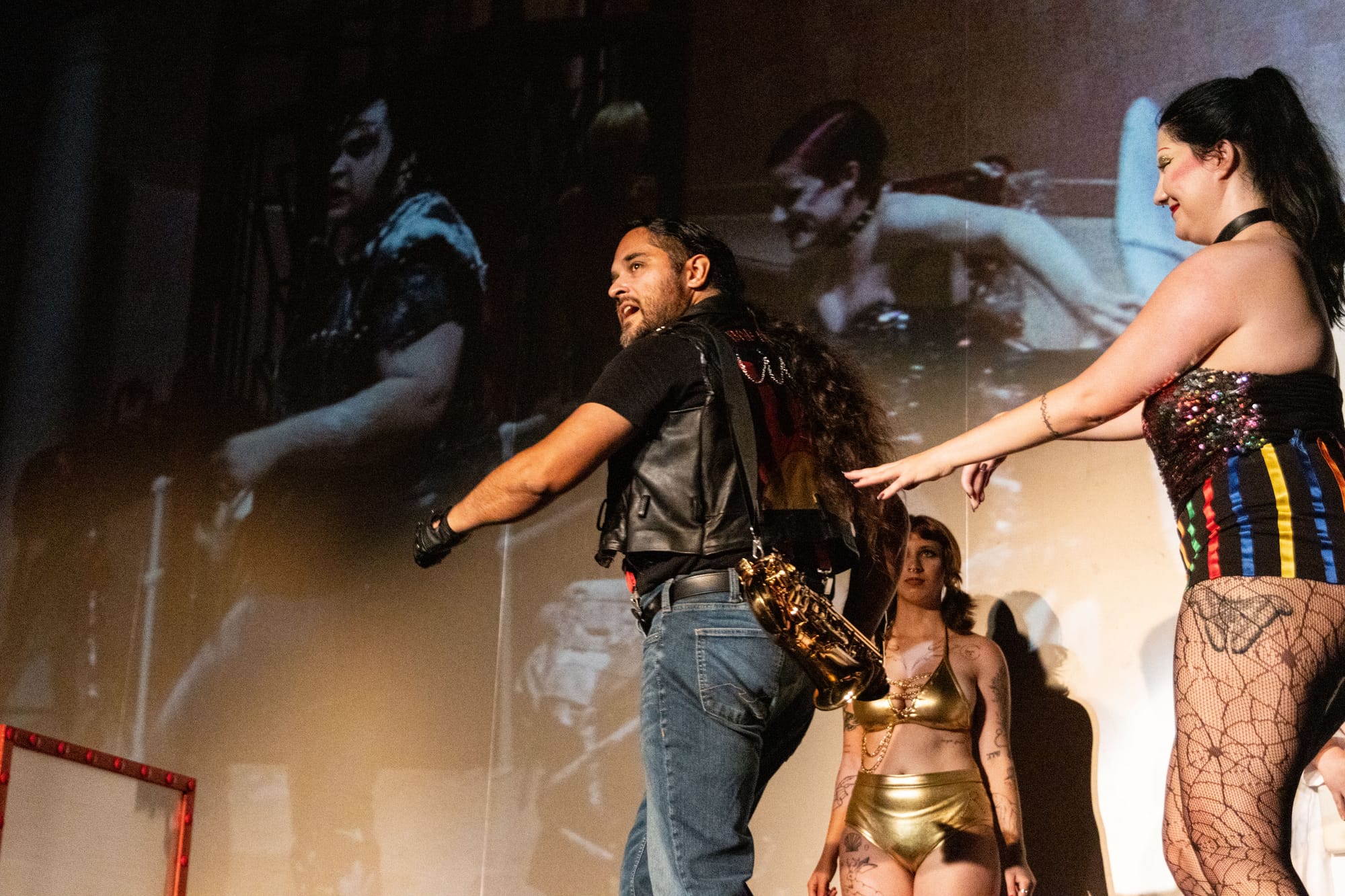 People dance on stage in front of a movie screen