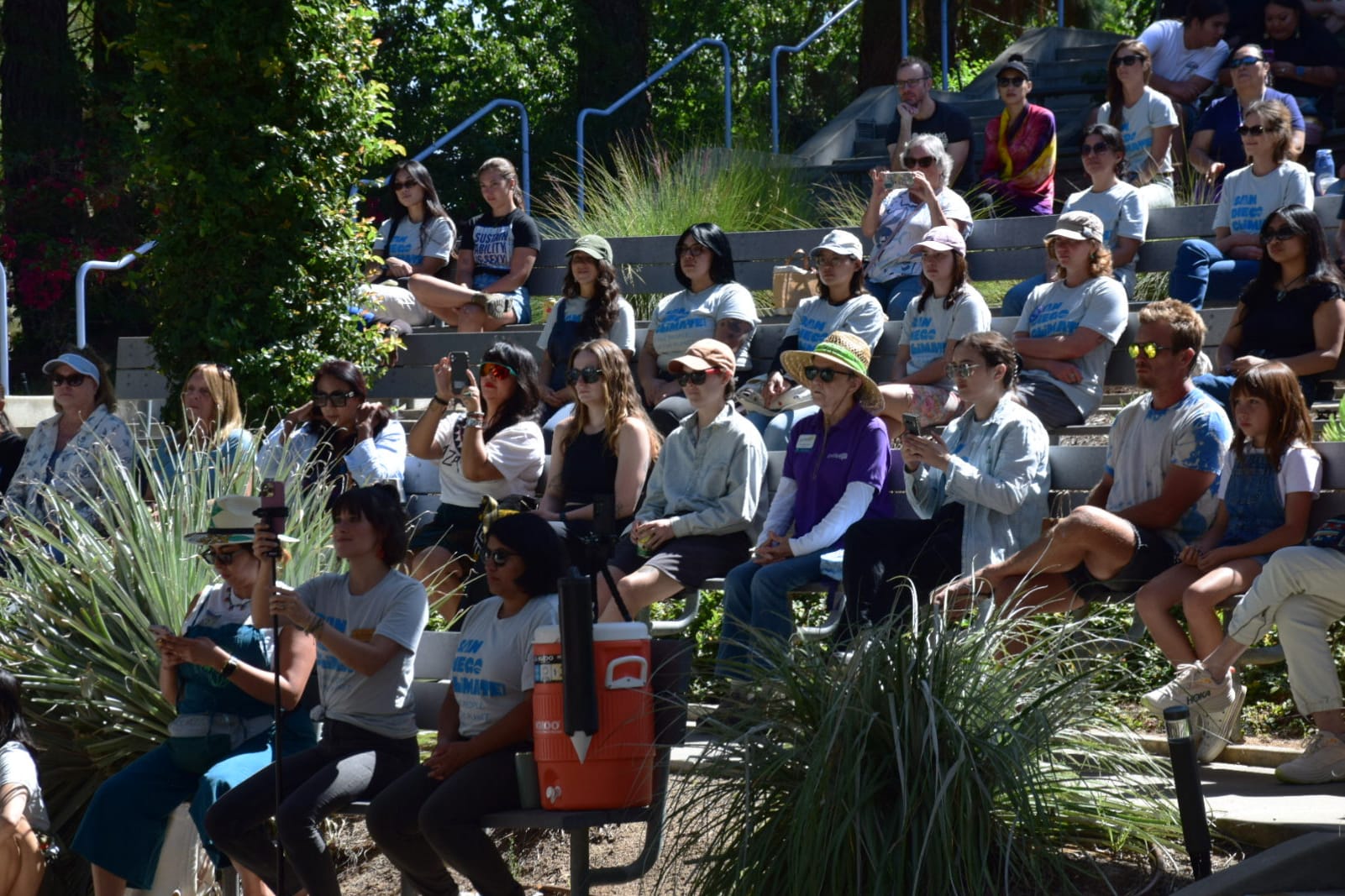 Rows of people sit watching performances in an amphitheater