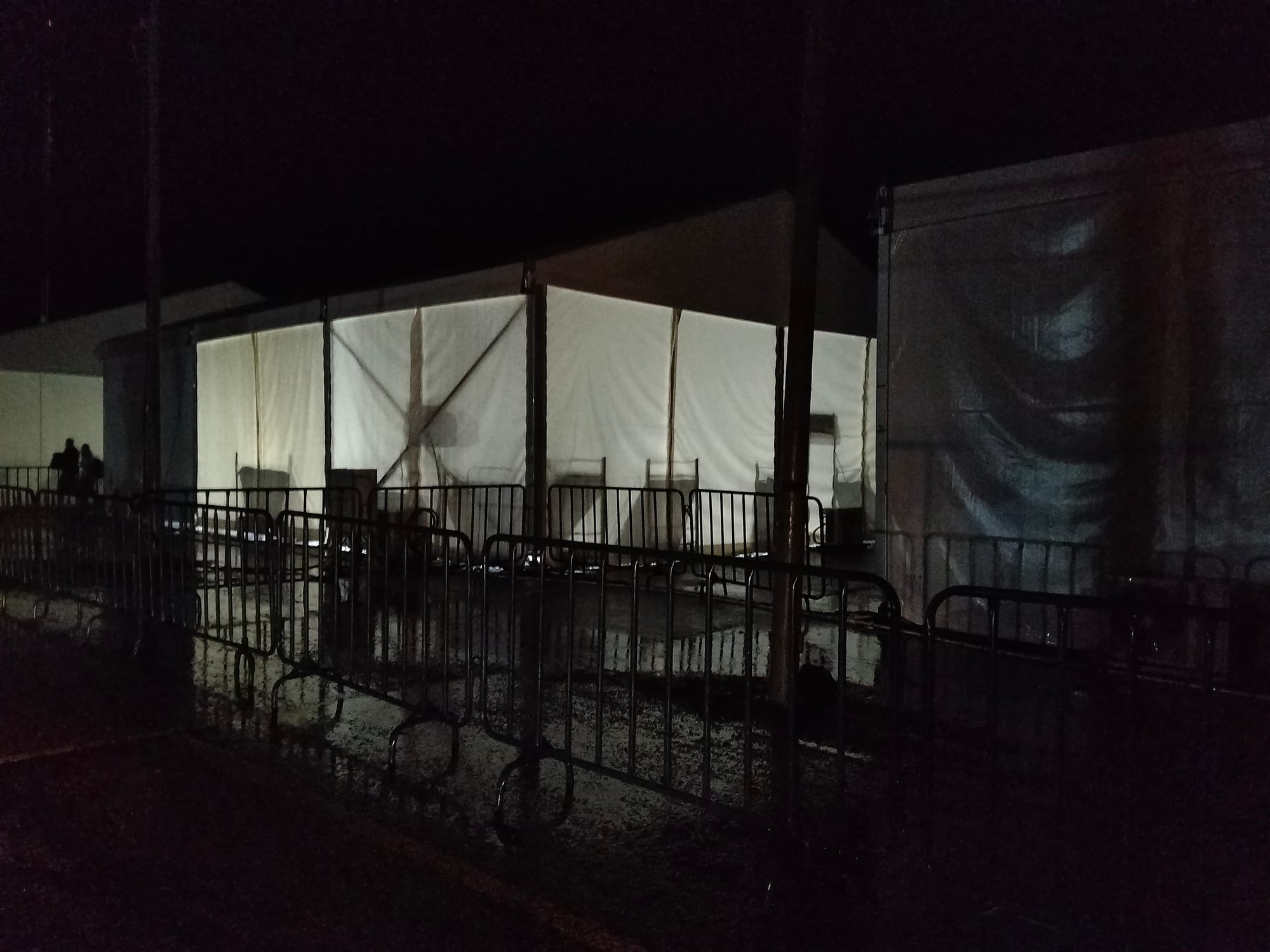A light in a white tent shows the silhouettes of beds at night