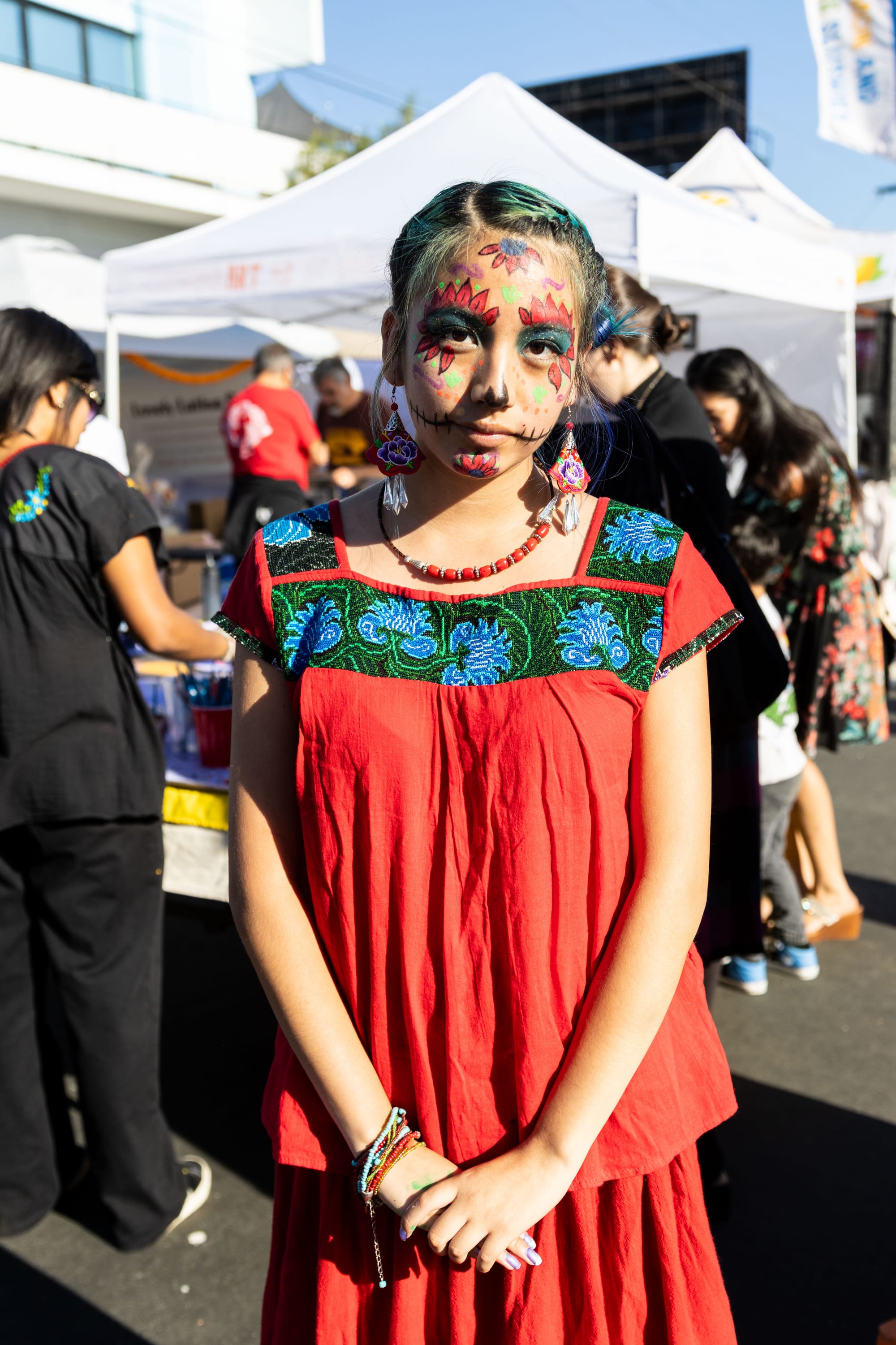 A young girl stands up for a photo wearing a red blouse and skirt.