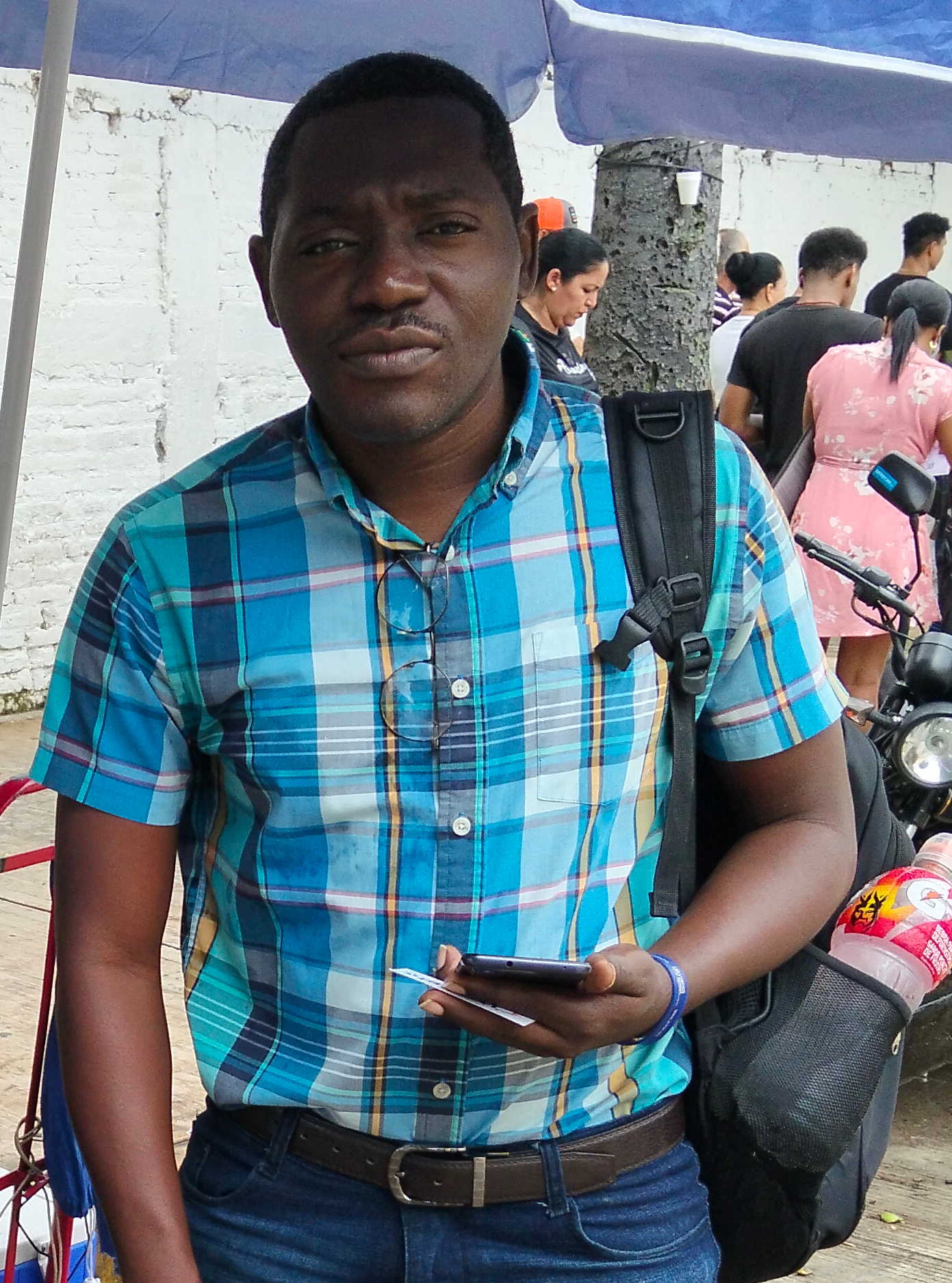 A man in a blue plaid shirt poses for a photo