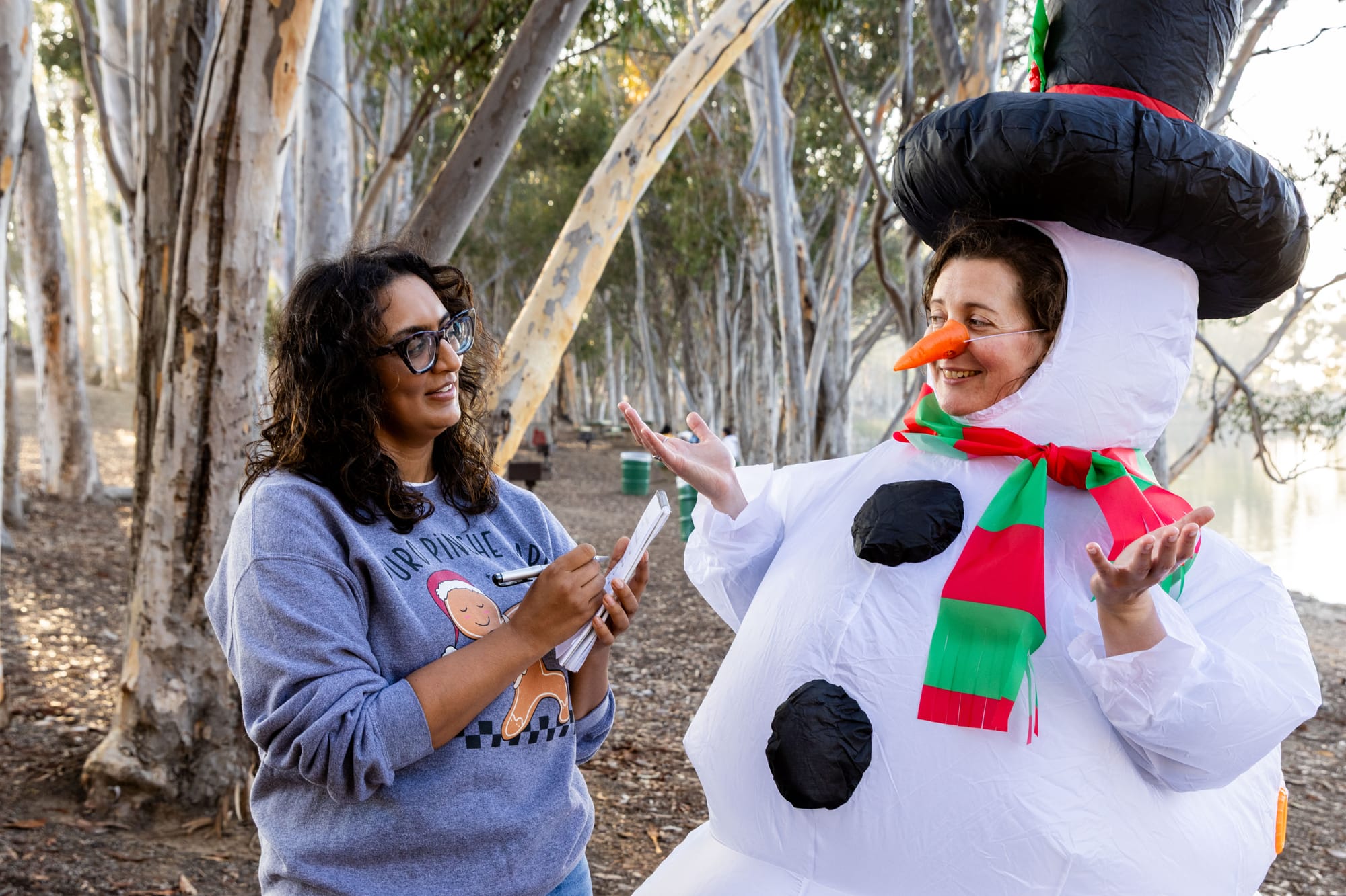 A person takes notes while interviewing someone dressed in a snowperson costume.