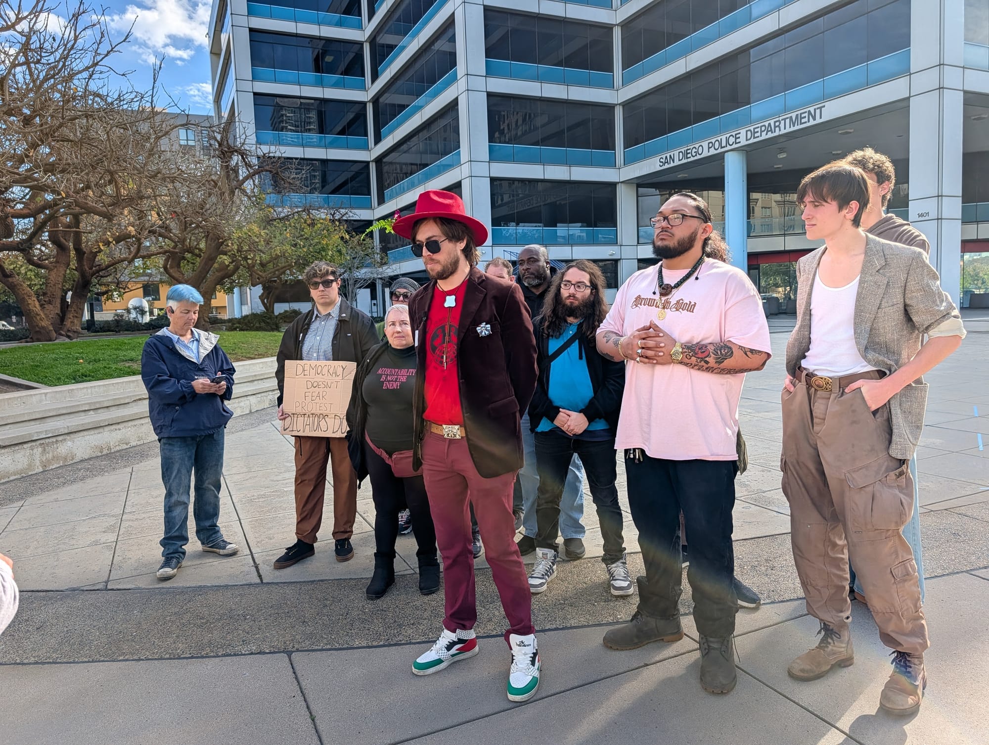 A group of protestors stand outside the San Diego Police Department. 