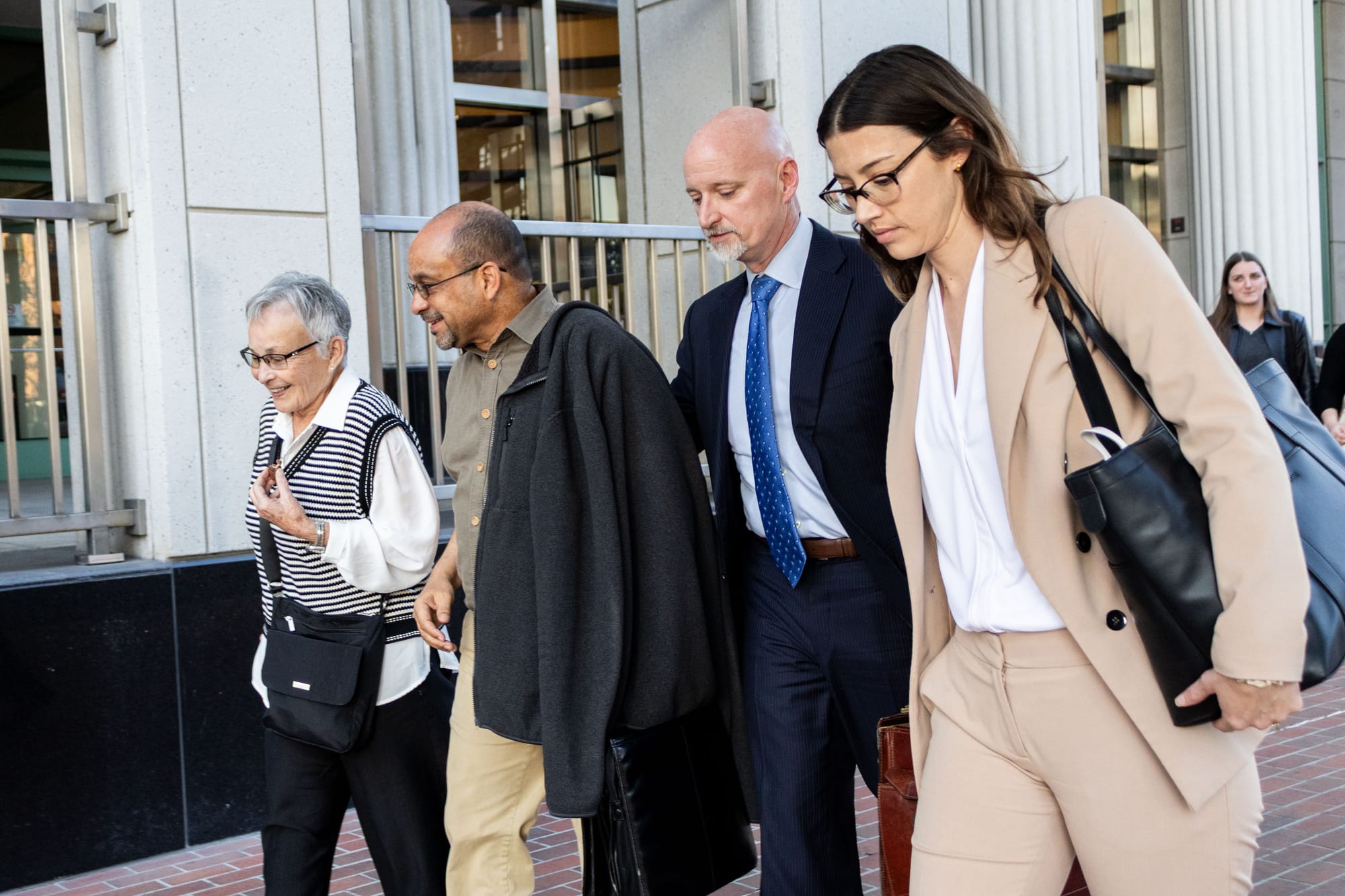 Two women and two men walk toward the left of the frame.