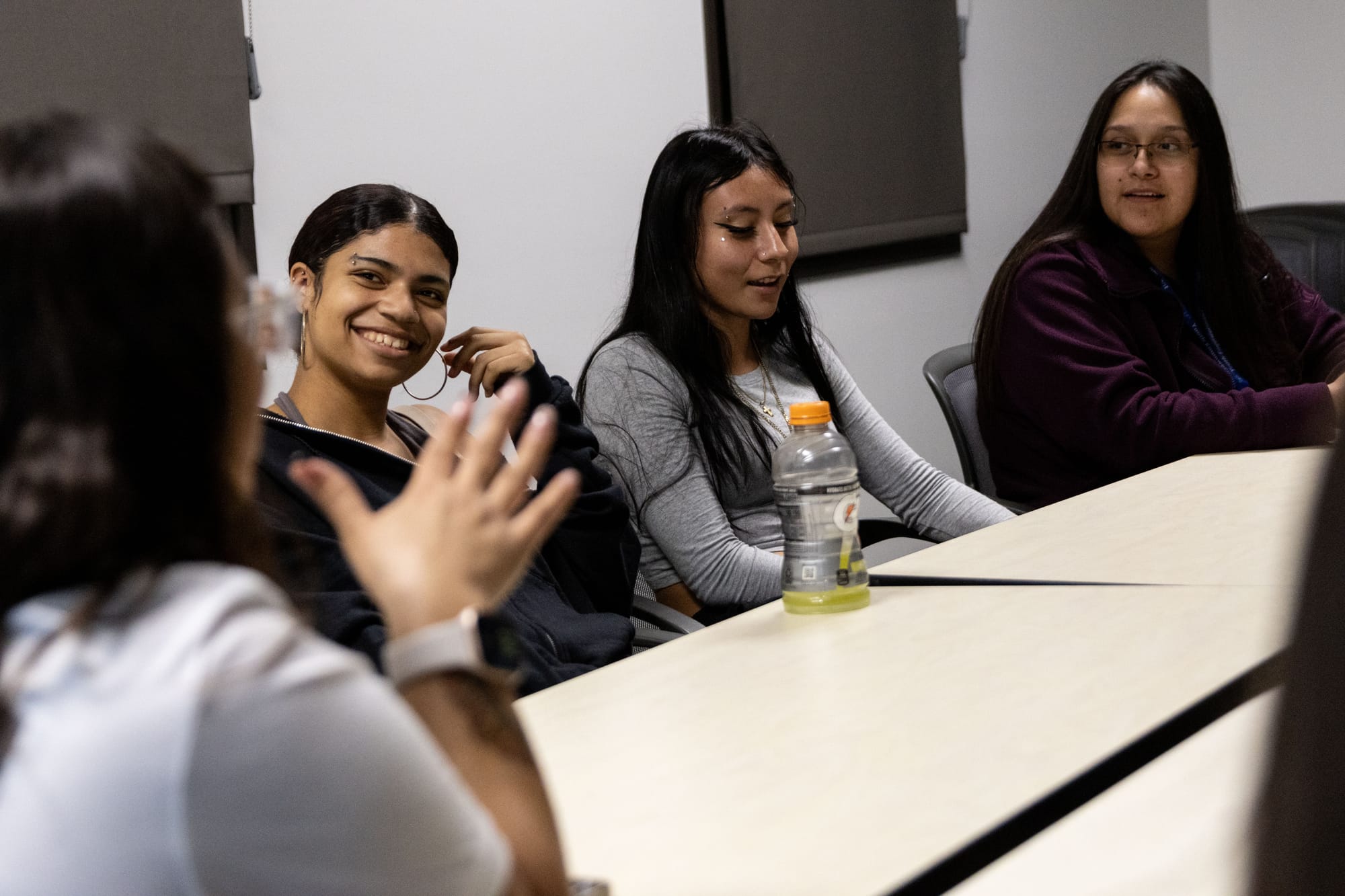 Teens sit around a table talking with adults.