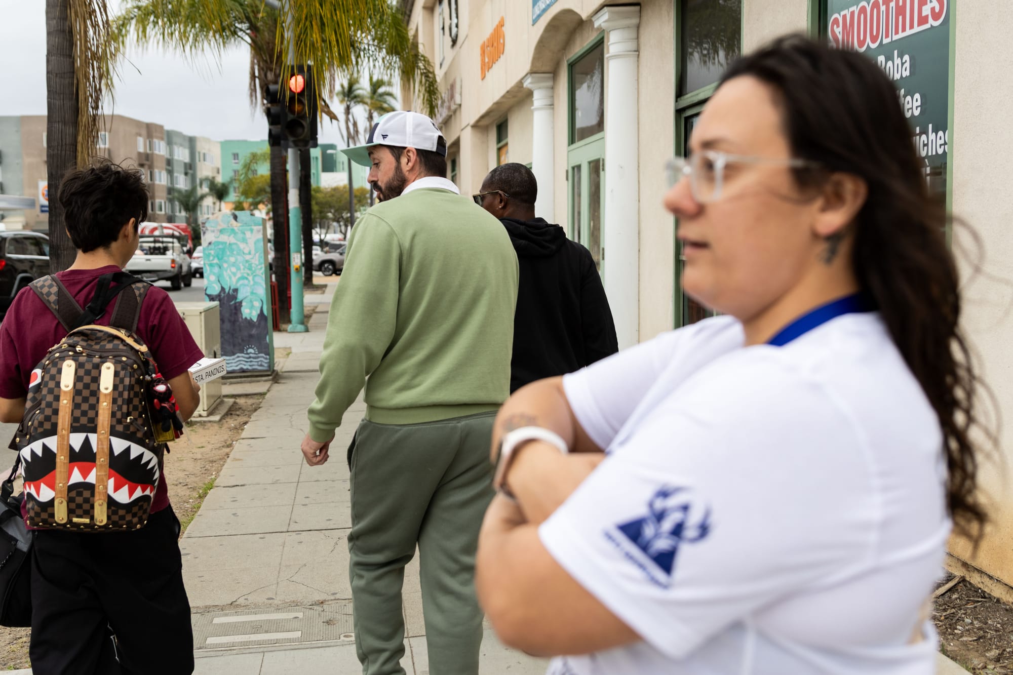 Adults and students walk and talk on a street sidewalk.