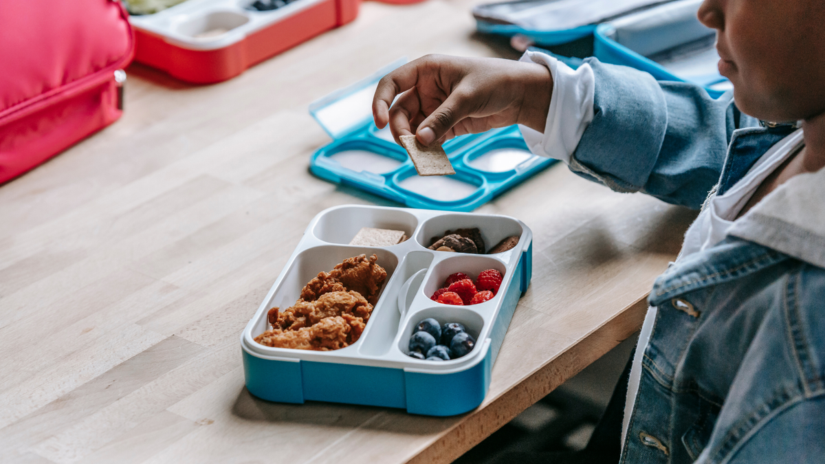 A closeup of a kid eating a school lunch 