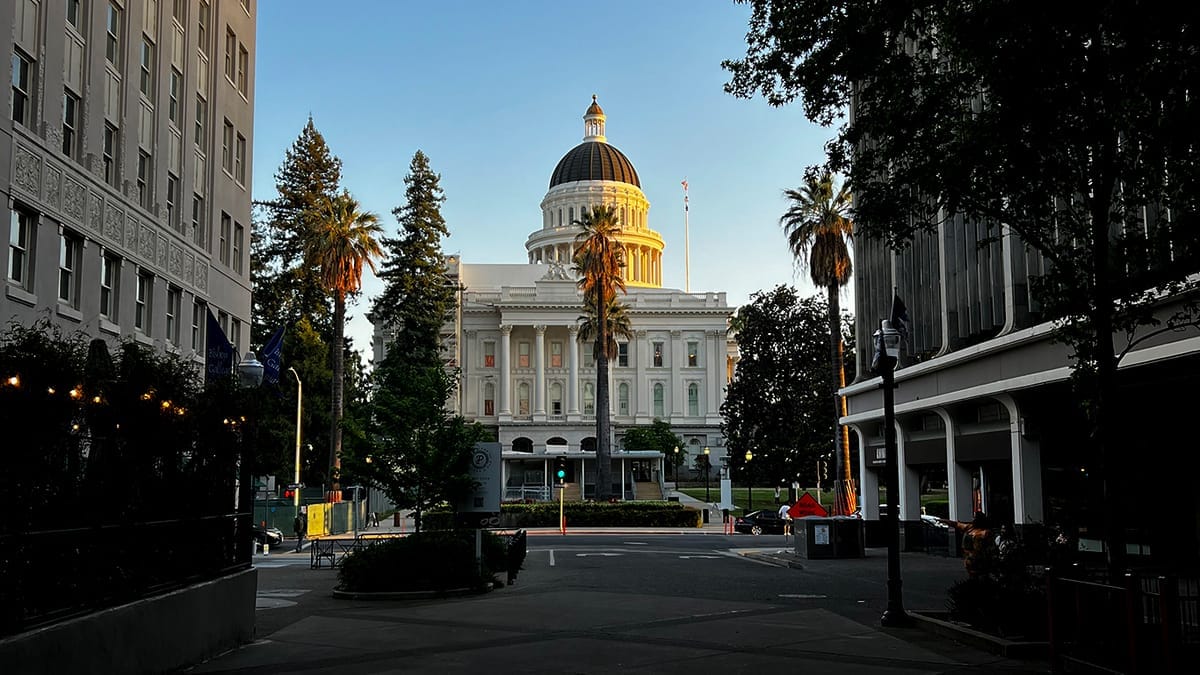 Picture of a capitol building with a dome on top and palm trees in front