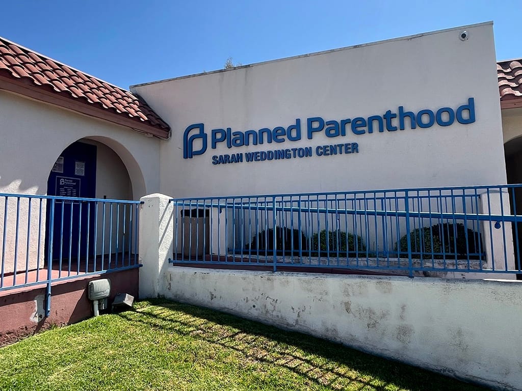 Picture of a building with a tiled roof and the words "Planned Parenthood Sarah Weddington Center" on the side.
