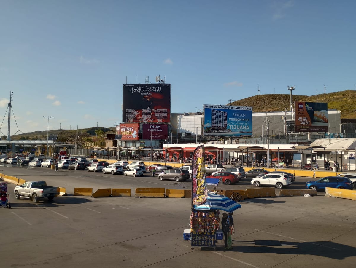 A snack stand is in front of a line of cars waiting to cross through booths