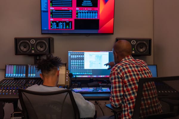 Two people work at a computer media station 