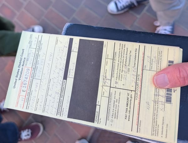 A hand holds a yellow ticket with faint writing on it